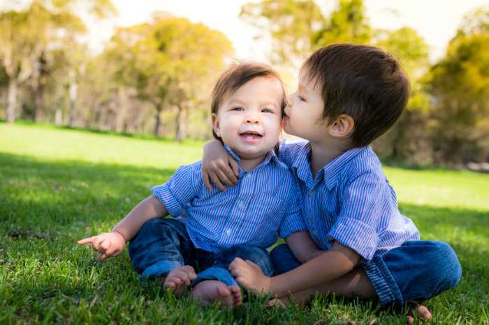 An elder brother giving his baby brother a kiss on the cheek